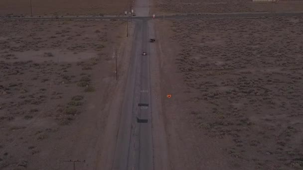 AERIAL: Flight over loneley abandoned desert road with red car driving in the distance — 图库视频影像