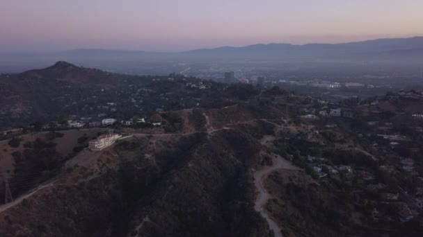 AERIAL: Sobre Hollywood Hills al amanecer con vista a las colinas y el valle y líneas eléctricas en Los Ángeles vista — Vídeos de Stock