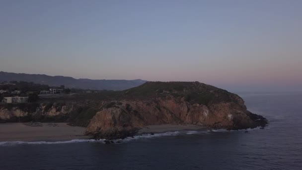 AERIAL: lento Malibun yli, Kalifornia näkymä rannalle Paficic ocean auringonlaskun aikaan vuoren kalliolla — kuvapankkivideo