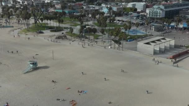 AERIAL: Let směrem k Benátkám Beach skatepark a stravování procházka s palmami a kolo pruh, Sunny, Los Angeles California — Stock video