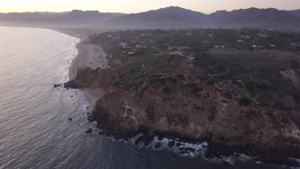 AERIAL: lot nad Malibu, Kalifornia widok na plażę Shore Line Paficic ocean o zachodzie słońca z urwiskiem górskim — Wideo stockowe