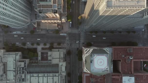 AERIAL: Slow Birds eye Veja o voo sobre o centro de Los Angeles, Califórnia, na bela Sunrise Light, com vista para telhados de arranha-céus e tráfego de carros passando — Vídeo de Stock