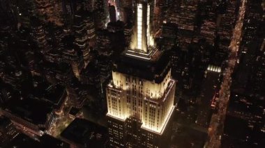 Gökyüzündeki ikonik Empire State binası üzerinde nefes kesici bir çember oluşturarak paralel caddeler ve kavşakları aydınlattı Manhattan, New York 'ta gece yarısı konutlar ve ofis binaları.