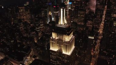 Gökyüzündeki ikonik Empire State binası üzerinde nefes kesici bir çember oluşturarak paralel caddeler ve kavşakları aydınlattı Manhattan, New York 'ta gece yarısı konutlar ve ofis binaları.