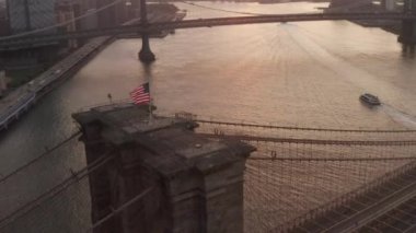 Brooklyn Köprüsü üzerinde Amerikan bayrağı ve East River manzaralı New York City Skyline 'a yakın bir daire uçuşu. 