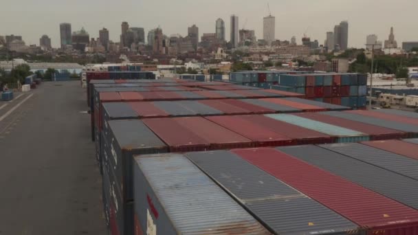 AERIAL: Volando sobre contenedores de carga industrial rojo y azul en muelles con la ciudad de Nueva York con horizonte en el fondo en el día nublado — Vídeos de Stock
