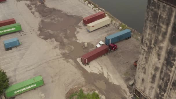 AERIAL: Siguiendo el camión de carga con carga pesada en los muelles de la ciudad de Nueva York Día gris nublado — Vídeo de stock