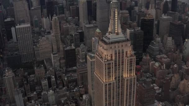 AERIAL: Primer plano del Empire State Bulding al atardecer con las luces encendidas — Vídeo de stock