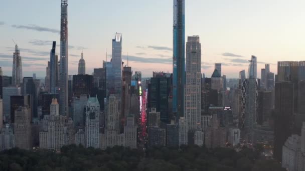 АЭРИАЛ: Вид на 7-ю авеню Траффик и Таймс-сквер над Центральным парком Нью-Йорка на закате с огнями Сити — стоковое видео
