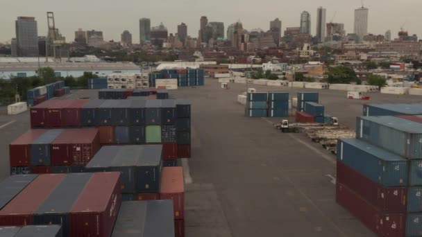 AERIAL: Vliegen over rood en blauw industriële vrachtcontainers in dokken met New York City met skyline op de achtergrond op bewolkte dag — Stockvideo