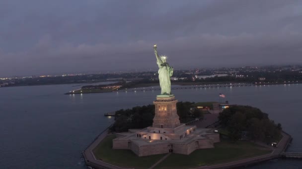 AERIAL: Circle Statue of Liberty prachtig verlicht in de vroege ochtend licht New York City — Stockvideo