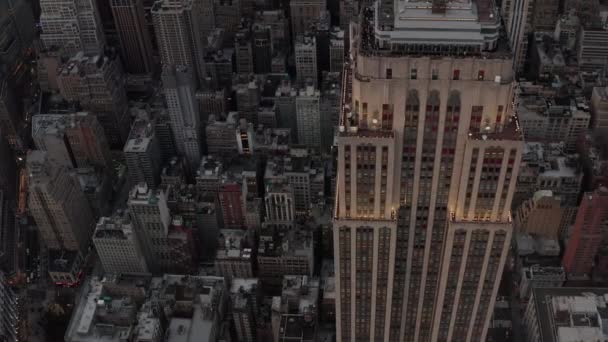 AERIAL: Primer plano del Empire State Bulding al atardecer con las luces encendidas — Vídeo de stock