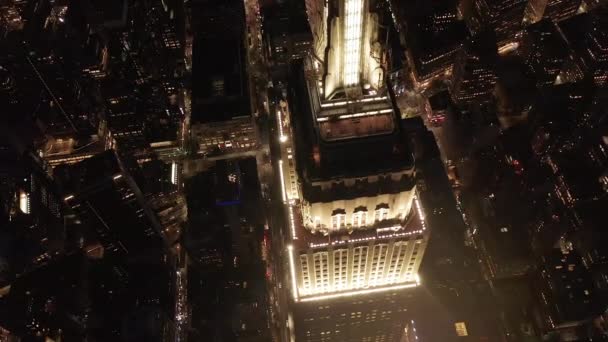 AERIAL: Adembenemende cirkel over het iconische Empire State Building boven verlichtte parallelle wegen en knooppunten residentiële flatgebouwen en kantoorgebouwen in Midtown Manhattan, New York City 's nachts — Stockvideo