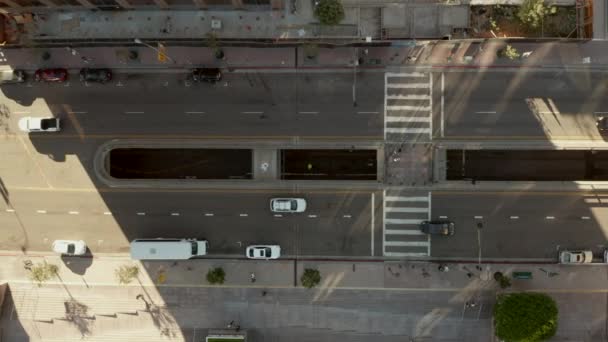 AERIAL: fiatalember feküdt az utcán lassú Madarak szem A repülés felett Downtown Los Angeles California Grand Avenue gyönyörű Sunrise Light kilátással a felhőkarcoló háztetők és az autó forgalom halad — Stock videók