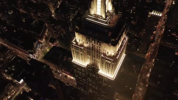 AERIAL: Häpnadsväckande cirkel över den ikoniska Empire State Building ovan lyste upp parallella avenyer och korsningar bostäder lägenheter och kontorsbyggnader i Midtown Manhattan, New York City på natten — Stockvideo