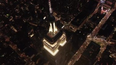 Gökyüzündeki ikonik Empire State binası üzerinde nefes kesici bir çember oluşturarak paralel caddeler ve kavşakları aydınlattı Manhattan, New York 'ta gece yarısı konutlar ve ofis binaları.