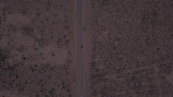 AERIAL: Birds View volo su solitario deserto abbandonato strada con auto rossa guida in lontananza — Video Stock