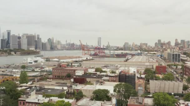 AERIAL: Over NYC Docks Warehouses towards industrial cranes on cloudy day with view of Manhattan Skyline in — 图库视频影像