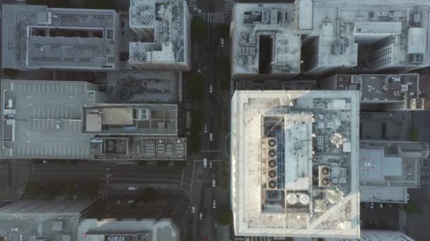 AERIAL: Slow Birds eye View flight over Downtown Los Angeles California in beautiful Sunrise Light with view of skyscraper rooftops and car traffic passing — Stock video