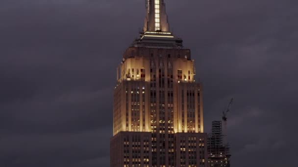 Πετώντας πάνω από το Empire State κτίριο τη νύχτα στο Μανχάταν περιβάλλεται από ουρανοξύστες σε πολυσύχναστη πόλη — Αρχείο Βίντεο