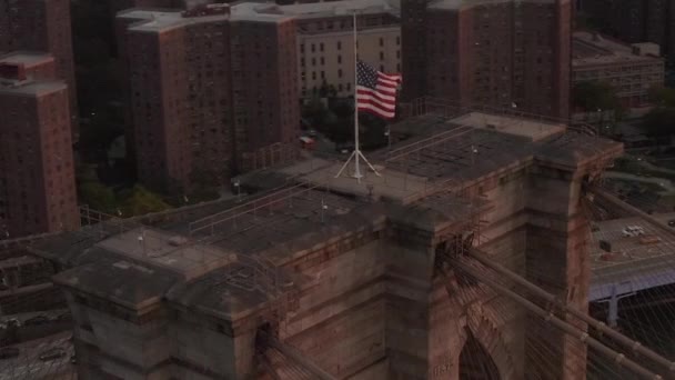 AERIAL: Feche o voo em círculo sobre Brooklyn Bridge com bandeira americana e nevoeiro Manhattan New York City Skyline — Vídeo de Stock