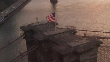 Brooklyn Köprüsü üzerinde Amerikan bayrağı ve East River manzaralı New York City Skyline 'a yakın bir daire uçuşu. 