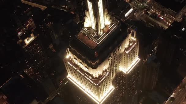 AERIAL: Adembenemende cirkel over het iconische Empire State Building boven verlichtte parallelle wegen en knooppunten residentiële flatgebouwen en kantoorgebouwen in Midtown Manhattan, New York City 's nachts — Stockvideo