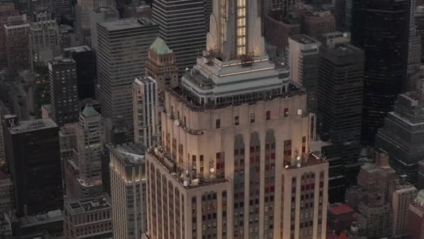 AERIAL: Primer plano del Empire State Bulding al atardecer con las luces encendidas — Vídeos de Stock