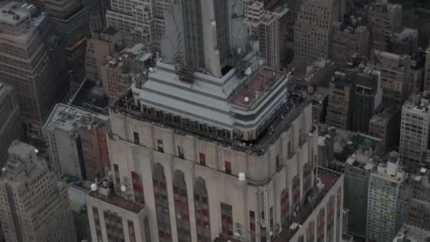 AERIAL: Vackra skott cirklar Empire State byggnaden i Manhattan omgiven av lie skrapor i upptagen stad på molnig dag — Stockvideo