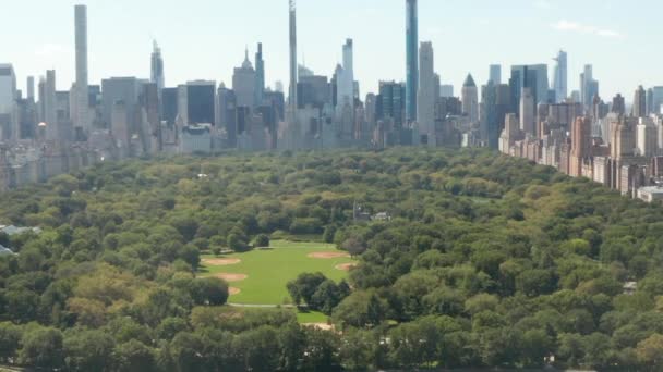 AERIAL: Hermosa vista del Central Park con el lago y el horizonte de Manhattan en el fondo en el soleado día de verano, Nueva York — Vídeos de Stock