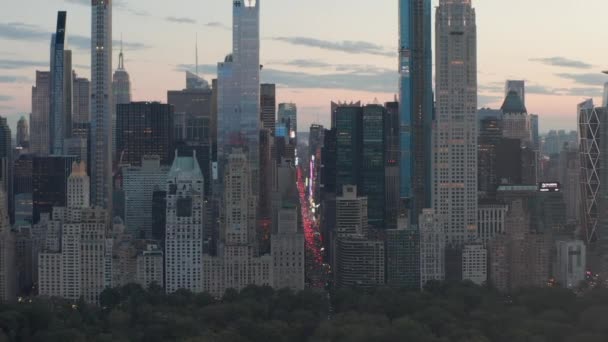 AERIAL: Vista da 7th Avenue Traffic e Times Square sobre o New York City Central Park ao pôr do sol com luzes da cidade — Vídeo de Stock