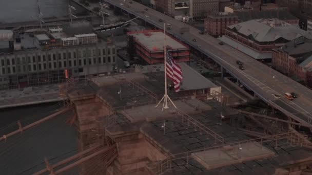 AERIAL: zárt kör repülés felett Brooklyn Bridge amerikai zászló és ködös Manhattan New York City Skyline — Stock videók