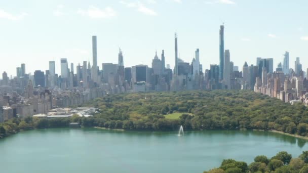AERIAL: Krásný výhled na Central Park s jezerem a Manhattan panorama v pozadí na slunném letním dni, New York City 
