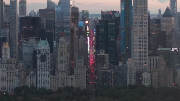 AERIAL: Vista da 7th Avenue Traffic e Times Square sobre o New York City Central Park ao pôr do sol com luzes da cidade — Vídeo de Stock