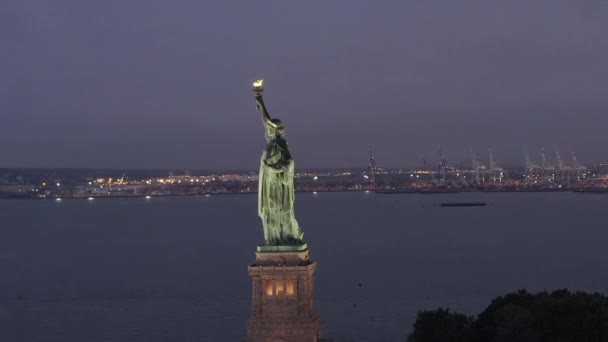 AERIAL: Estatua de la Libertad en círculo bellamente iluminada a primera hora de la mañana Nueva York — Vídeos de Stock