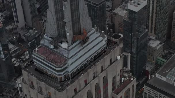 空気:曇り空の日に忙しい都市のスクラッパーに囲まれたマンハッタンのエンパイアステートビルを周回する美しいショット — ストック動画