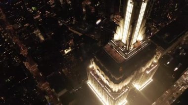 Gökyüzündeki ikonik Empire State binası üzerinde nefes kesici bir çember oluşturarak paralel caddeler ve kavşakları aydınlattı Manhattan, New York 'ta gece yarısı konutlar ve ofis binaları.