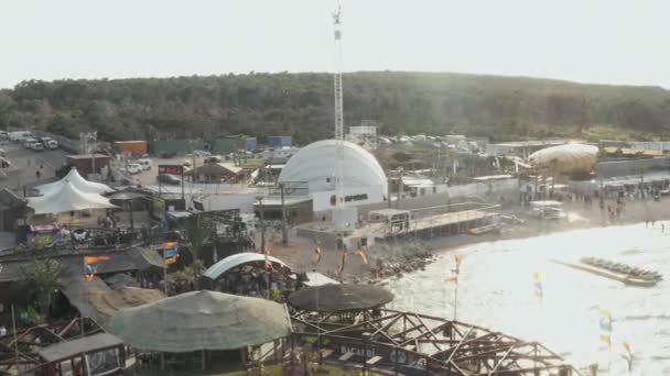 AERIAL: Krásný Beachclub v Noválii, Chorvatsko u oceánu za slunečného počasí a vlajek, palem a modrých vln — Stock video