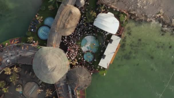 AERIAL: Birdsview de la gente bailando fiesta en el hermoso club de playa en Novalia, Croacia con el océano en tiempo soleado y banderas, palmeras y piscinas — Vídeo de stock
