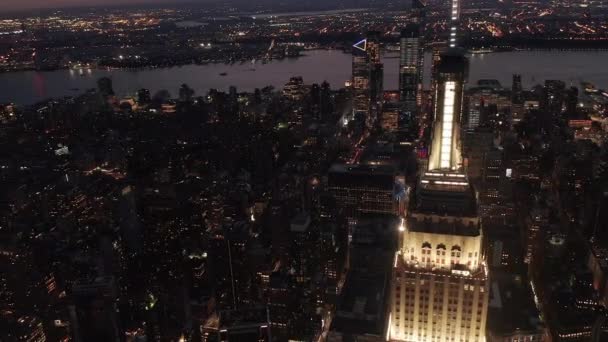 AERIAL: Voando acima iluminado avenidas paralelas e junções, condomínios residenciais e edifícios de escritórios em Midtown Manhattan, Nova York à noite. Infraestrutura rodoviária em metrópole, rio Hudson — Vídeo de Stock