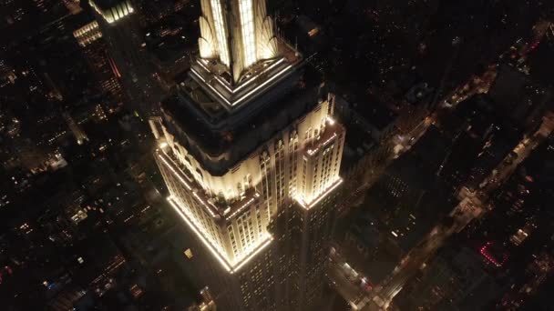 Epický záběr z blízka helikoptéry říšského státu, vypouklé nad osvětlenými paralelními uličkami a křižovatkami obytných domů a kancelářských budov v Midtown Manhattan, New York City v noci — Stock video
