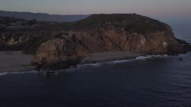 Malibu, California 'da sahil şeridi manzaralı Paficic Okyanusu üzerinde gün batımında dağ yamacıyla uçmak