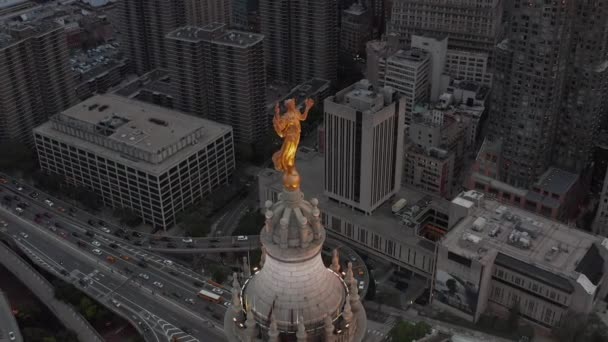 AERIAL: Кругом золотая статуя в Нью-Йорке с автомагистралями и оживленным городом — стоковое видео