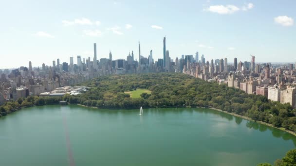 AERIAL: Bela vista do Central Park com lago e Manhattan Skyline em segundo plano no dia ensolarado de verão, Nova York — Vídeo de Stock