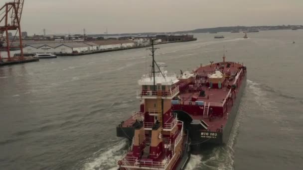 AERIAL: Siguiendo el gran buque de carga rojo en los muelles de la ciudad de Nueva York en un día nublado — Vídeos de Stock