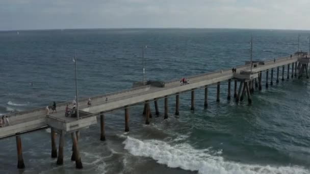 AERIAL voo ao lado do cais em Venice Beach, Los Angeles Califórnia em tempo nublado com ondas no oceano — Vídeo de Stock