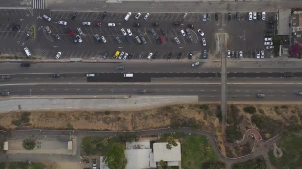 AERIAL: Vista de Birdseye del muelle de Santa Mónica, estacionamiento de Los Ángeles y PCH de la carretera de la costa del Pacífico con los coches que entran en la autopista — Vídeo de stock