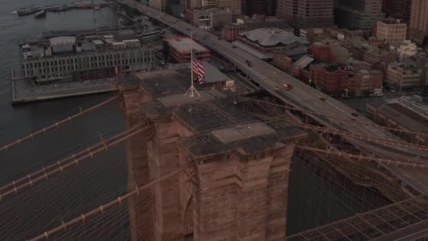 Närbild cirkelflygning över Brooklyn Bridge med amerikansk flagga och dimmiga Manhattan New York City Skyline — Stockvideo