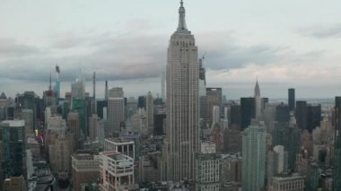 Manhattan 'daki Empire State binasında bulutlu bir günde kalabalık bir şehirde tırpancılarla uçmak. 