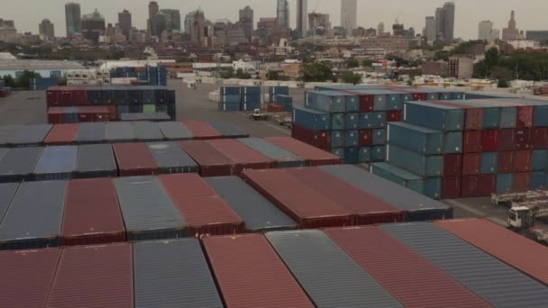 АЭРИАЛ: Пролетая над красными и синими промышленными грузовыми контейнерами в доках с Нью-Йорком на фоне облачного дня — стоковое видео